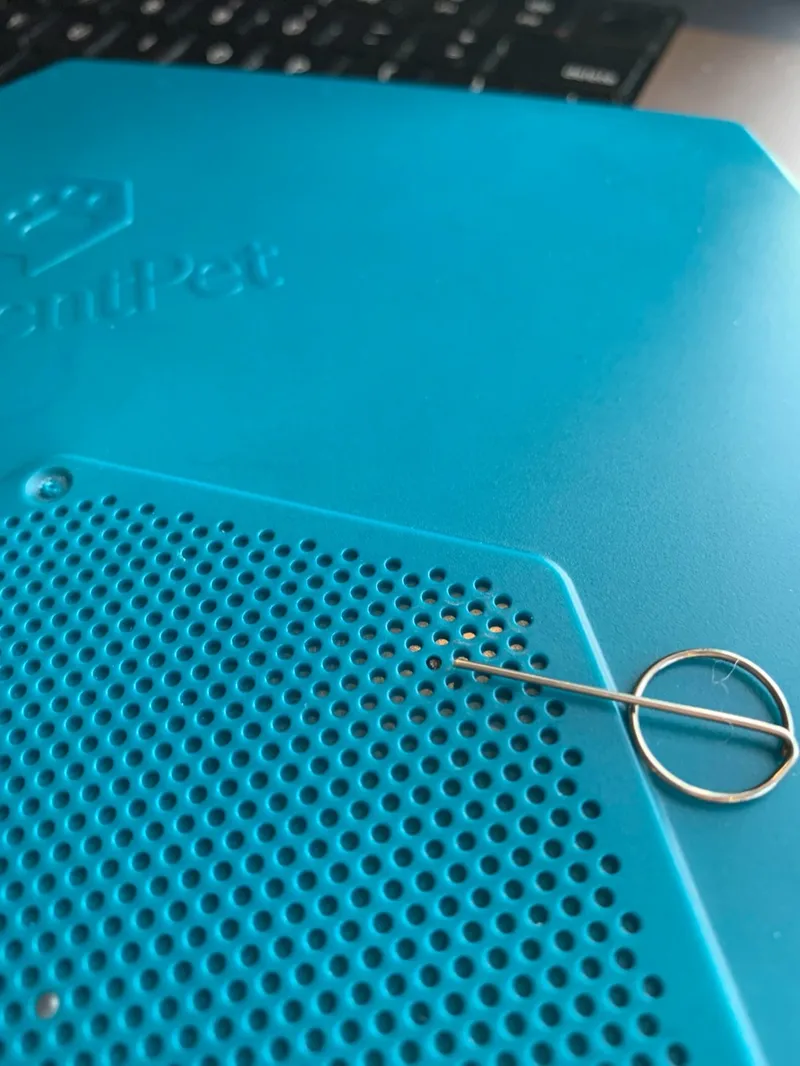 The linking pin inserted into one hole of the Base speaker grill, where the hidden hardware reset button is.