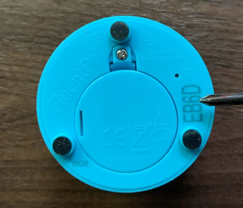 The bottom of a Connect Button, with a screwdriver tip pointing at the 4-character ID etched near the edge.